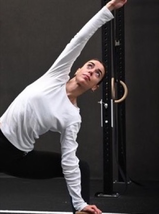 Manon en posture du triangle, bras tendu vers le plafond de la salle.